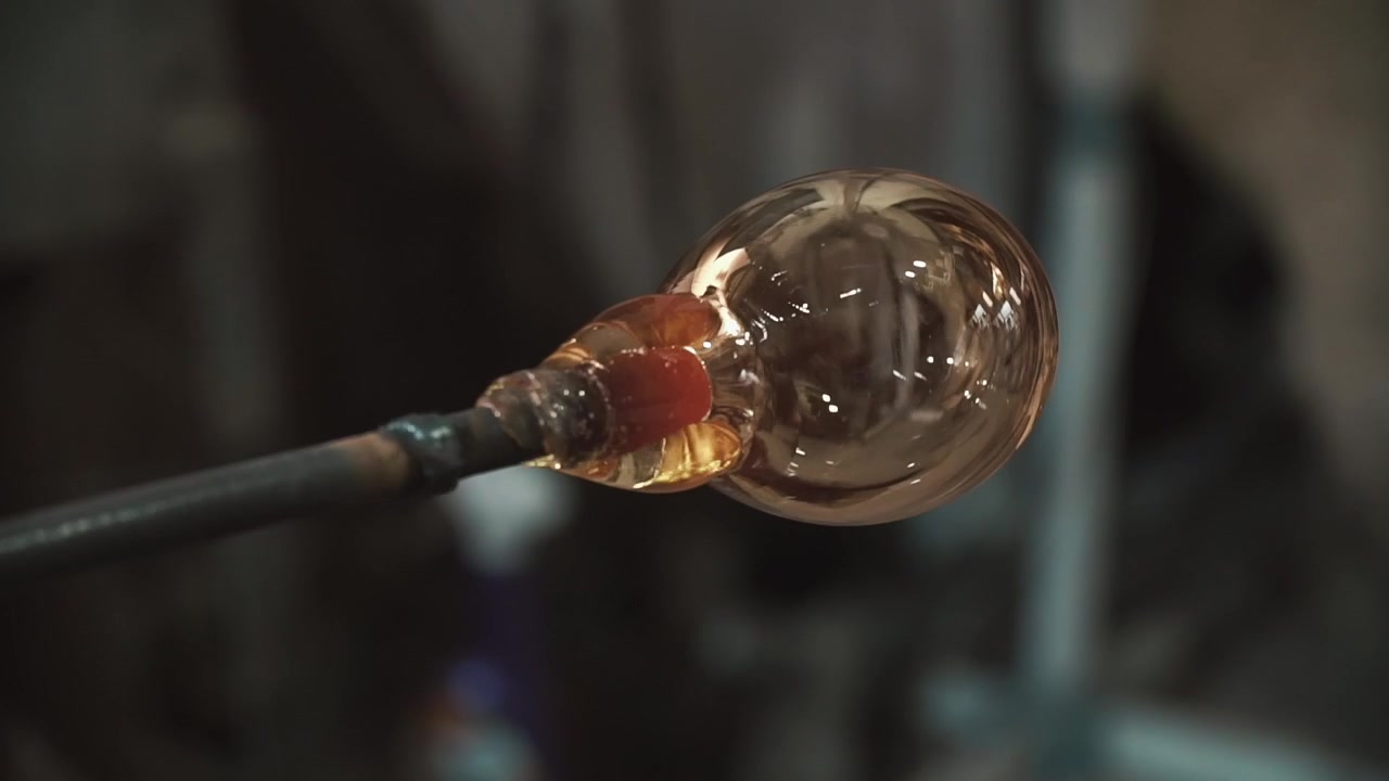 Närbild på smält glas som formas på en blåspipa