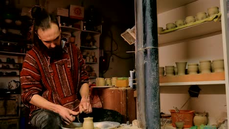 professional potter shaping mug with special tool in pottery workshop