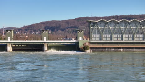 zoomed drone panning shot of water falling down over birsfelden hydro power plant in autumn time