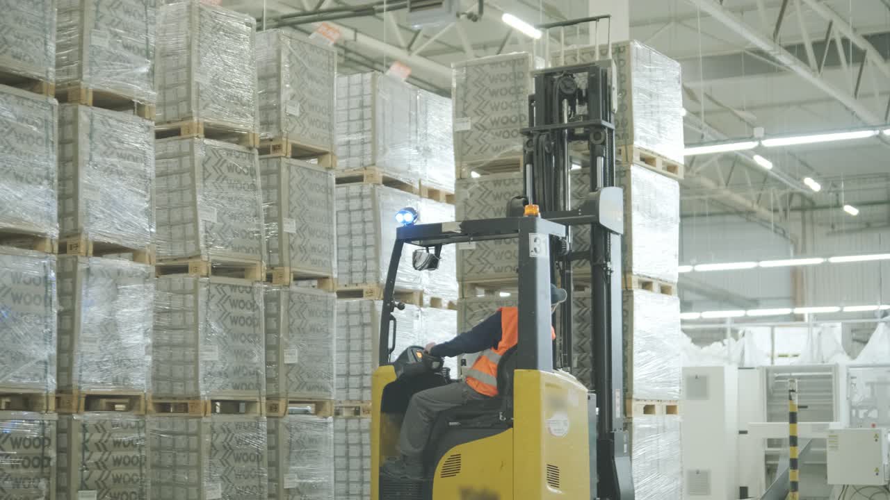 Operaio di magazzino che manovra un carrello elevatore tra pile di pallet