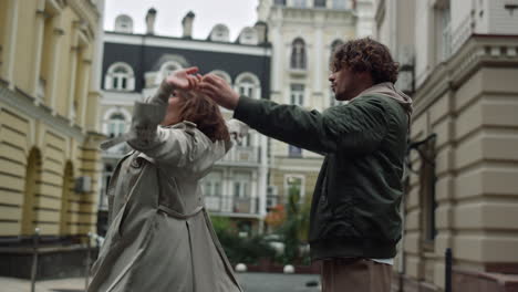 una pareja encantadora bailando en el fondo de la ciudad. hombre y mujer tomados de la mano al aire libre.