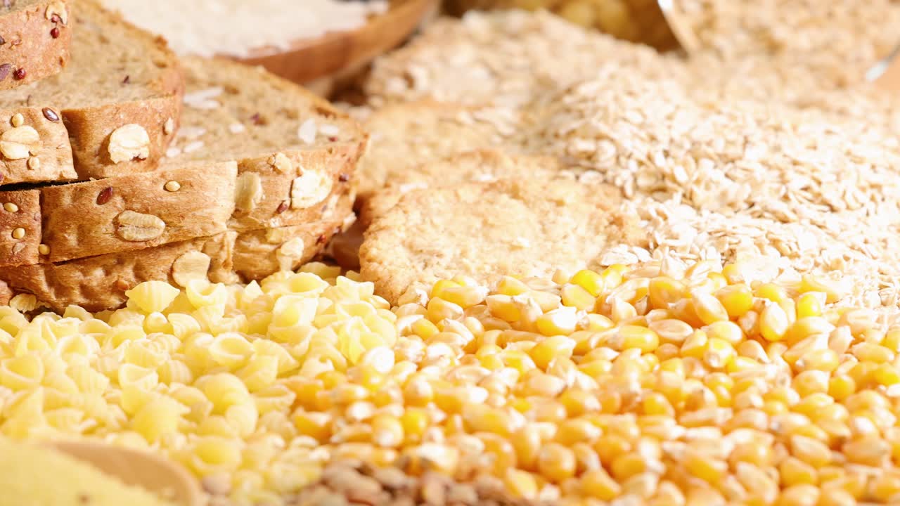 A variety of grains and breads displayed under warm lighting, showcasing textures and colors in a close-up arrangement