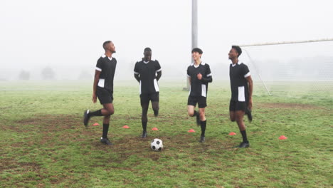 soccer players in black uniforms laughing and relaxing on foggy field