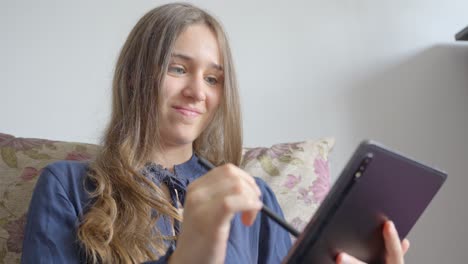 el uso alegre de la tableta de una joven hermosa y feliz: toma en cámara lenta de una cara sonriente con un lápiz electrónico