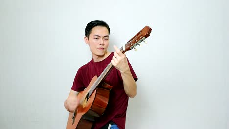 asian guy playing rock song with his vintage acoustic guitar