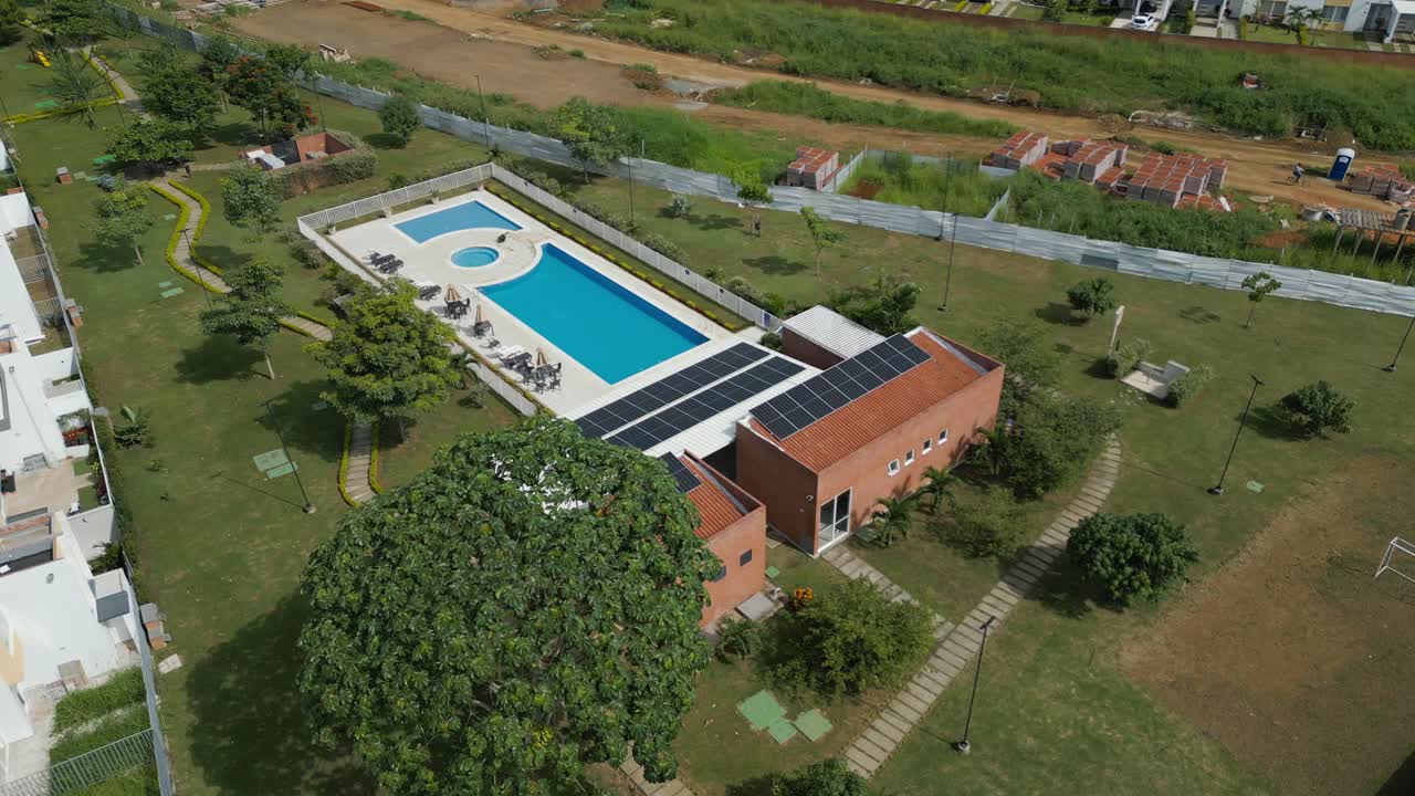 clubhouse de área residencial colombiana con paneles solares en el techo para producir electricidad limpia y una piscina, ubicada en los suburbios de cali, valle del cauca