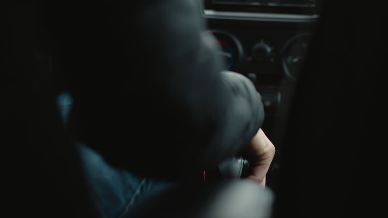 Driver shifts gear lever forward with practiced motion in manual transmission cabin, closeup view of hands guiding knob through gears, focus on control and tactile precision during driving journey