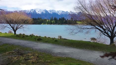 Antenne-Eines-Mädchens,-Das-Frisbee-Golf-In-Einem-Wald-Mit-Queenstown-Neuseeland-Und-Den-Südlichen-Alpen-In-Der-Ferne-Spielt