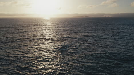 Vista-Aérea-De-Un-Detalle-De-Un-Barco-De-Pesca-Que-Regresa-A-Tierra-Después-De-Un-Largo-Día-En-El-Mar,-Con-La-Isla-De-Berlenga-En-Sealine