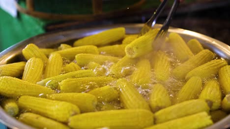 corn boiling in a large pot with tongs