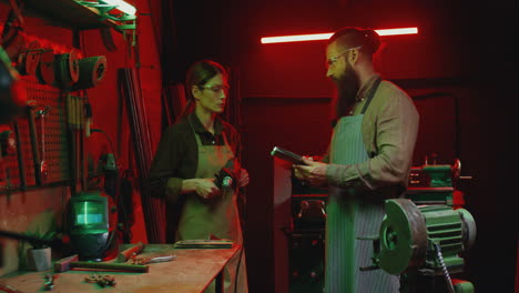 caucasian male and female workers talking while working in workshop