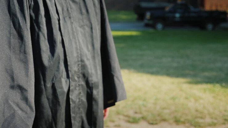 Uomo asiatico di successo in abiti da laurea riceve congratulazioni mentre gli stringono la mano.