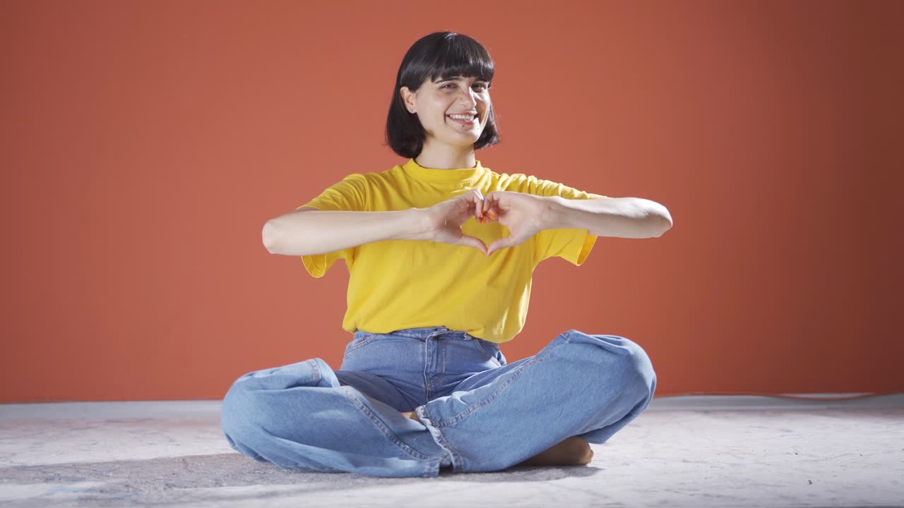 여성이 카메라를 위해 심장 기호를 만들고 있습니다.