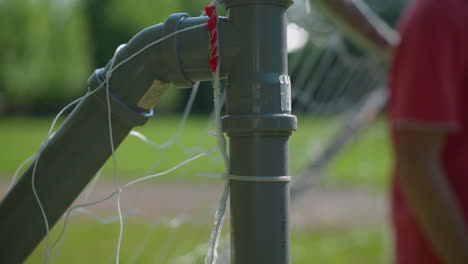 un primer plano de una pelota de fútbol golpeando la red del poste de gol mientras el portero borroso trata de salvar la pelota con su mano derecha después de que ha entrado en el poste de gol