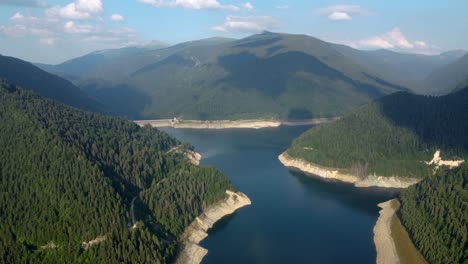 vidéo de drone cinématographique 4k volant au-dessus d'un barrage et d'un lac en roumanie parmi une belle forêt