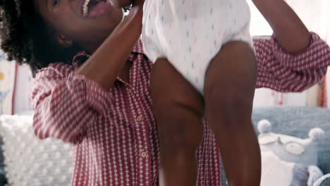 mother lifting baby daughter into the air and smiling at home