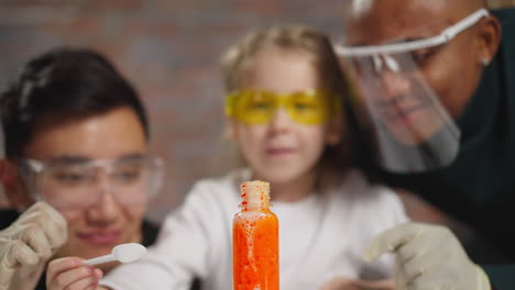 girl pours catalyst powder into bottle with color liquid