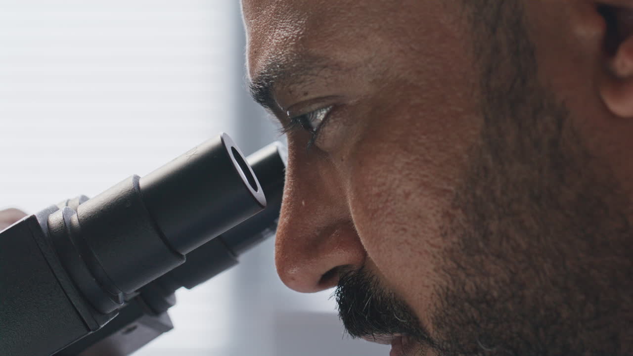 Scientist Studying Sample through Microscope in Laboratory