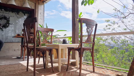 Cozy-Cafe-Interior-on-a-Balcony-adorned-with-Wooden-Chairs-and-Tables,-Creating-a-Warm-Atmosphere-on-a-Spring-Day