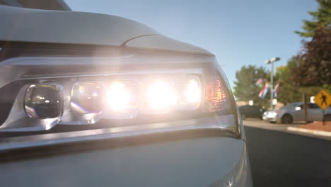 the camera moves along the front of a car to reveal headlights