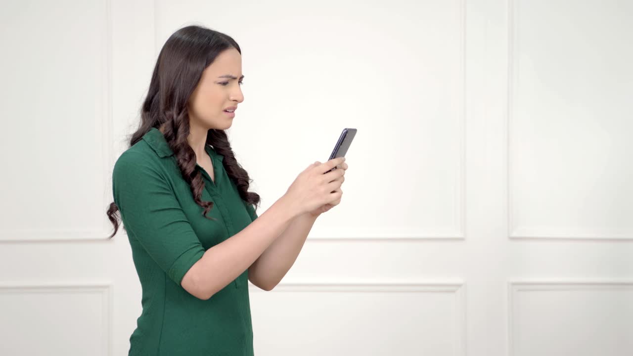 화난 인도 여성이 전화로 타이핑하고 있습니다.