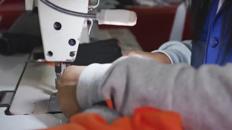 Close-up-view-of-woman-using-sewing-machine-in-factory-