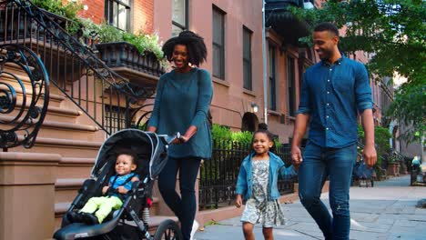 una joven familia negra con un cochecito caminando por la calle de brooklyn