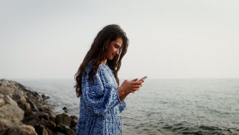 woman using a phone by the ocean