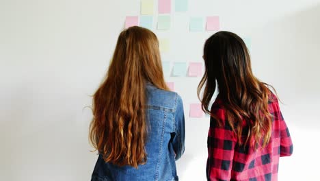 female executives discussing over sticky notes