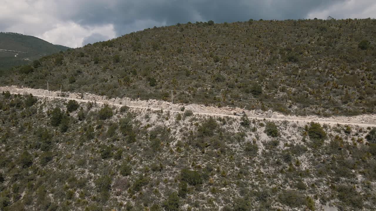 vista lateral del jeep en el camino a la montaña, camino de montaña en 4x4, tiro de seguimiento aéreo
