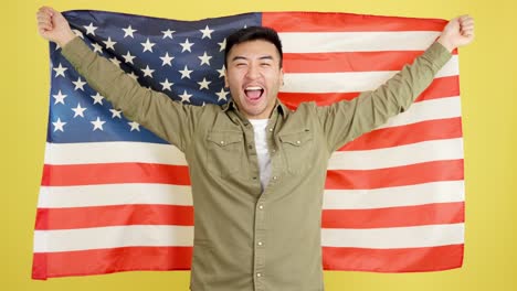 smiling asian man wrapped in the american flag against a yellow background