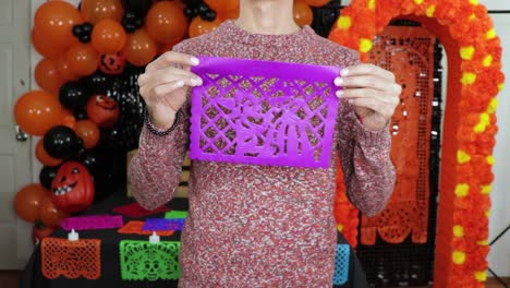 Holding-purple-handmade-perforated-papel-picado-paper-for-day-of-dead