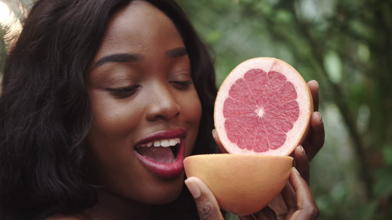 Scatto di un'affascinante giovane donna africana che tiene delle fette di pompelmo davanti al viso mentre posa