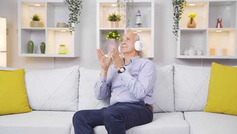 un anciano feliz en casa escuchando música tranquilamente con los auriculares.
