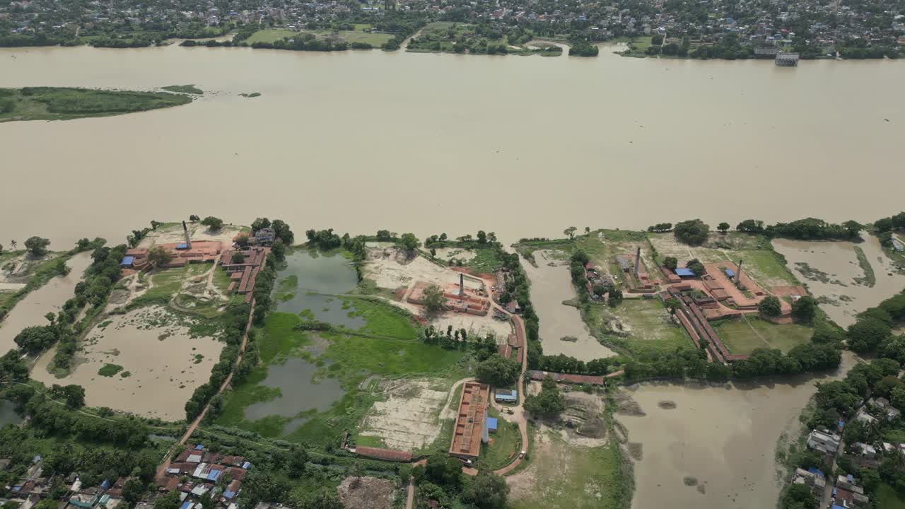 Ampia ripresa aerea del fiume Hooghly che scorre attraverso il Bengala Occidentale con tradizionali fornaci di mattoni e insediamenti rurali sulle rive.