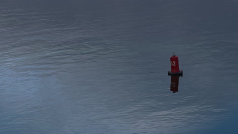 red buoy floating on still water drone shot. safe boats traveling concept.