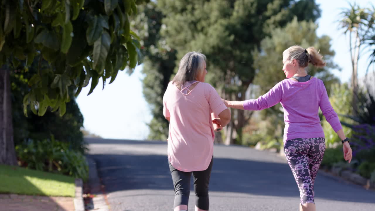 Multiracial female friends walking and chatting outdoors, enjoying sunny day together