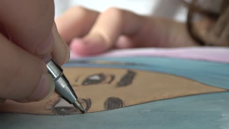 Close-up-of-girl-drawing-eyelashes-on-a-portrait-of-a-girl-with-a-pen