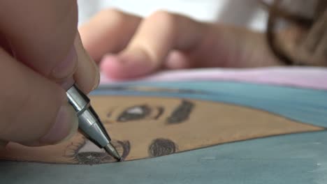 primer plano de niña dibujando pestañas en un retrato de una niña con una pluma