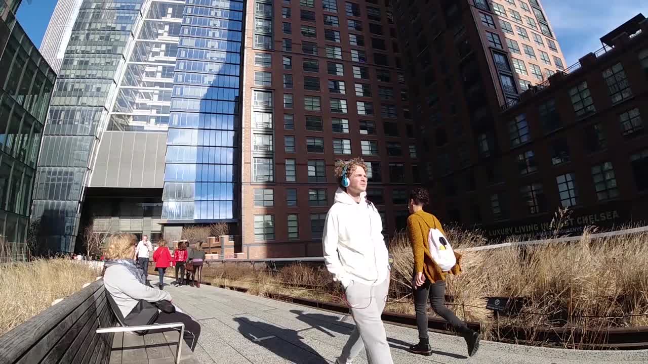 A cool guy with white hoodie and headphones on walks by in The High Line Park in New York City