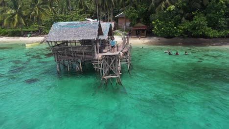 kid runs and jumps off the water with family in the beach of san pablo island philippines, aerial shot