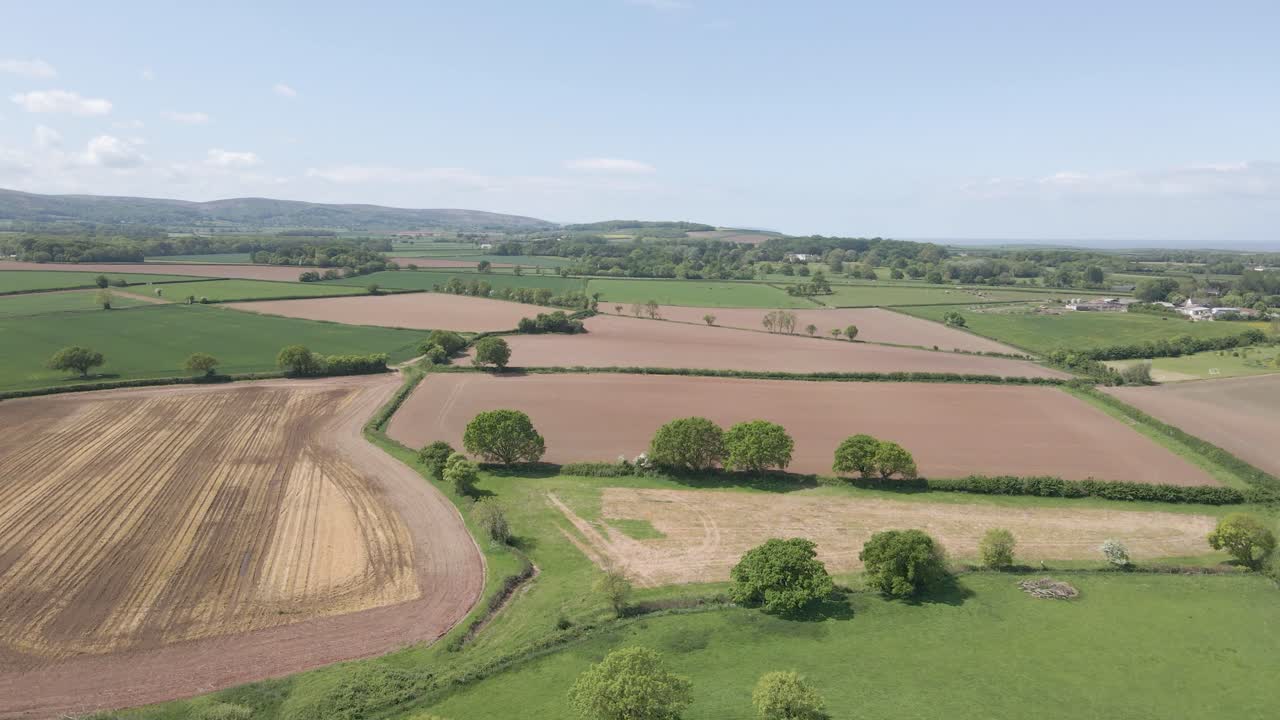 Arial view of Stogursey parish in the quantock hills Somerset. Drone slowly moving forward over the green fields and showing the quantocks on the background.