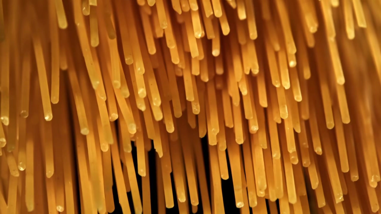 Spaghetti dorati che entrano a fuoco su sfondo nero