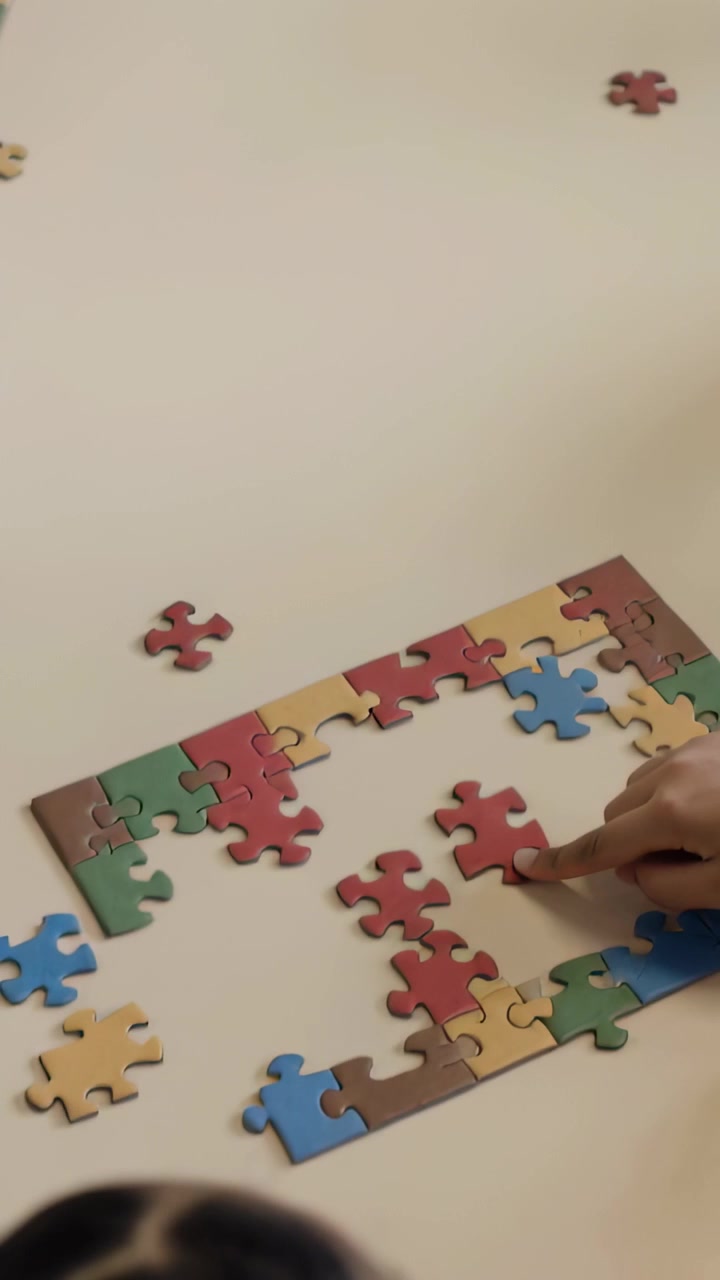 Vertical video: Placing 3 kids assembling jigsaw pieces at school, hand entering to finish puzzle