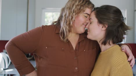 happy caucasian lesbian couple embracing and looking at each other at home