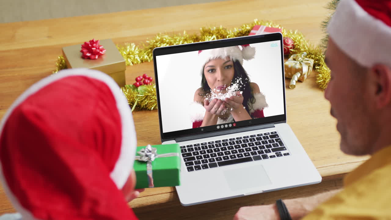 padre y hijo caucásicos con sombreros de santa usando una computadora portátil para una videollamada de navidad con una mujer en la pantalla