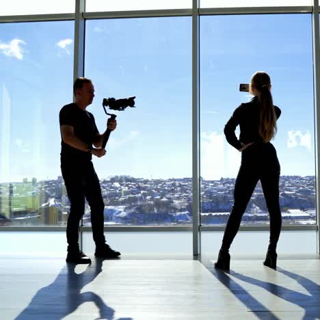 young woman doing selfie photo on a phone. back view of attractive girl and professional photographer indoors on windows background in sunny day