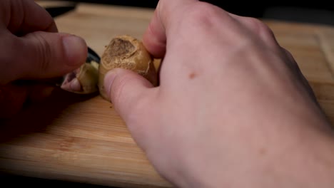 using a spoon to scrap the skin from a ginger tuber