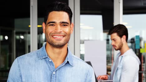 Retrato-De-Un-Ejecutivo-Masculino-Usando-Un-Teléfono-Móvil-Con-Su-Colega-En-Segundo-Plano