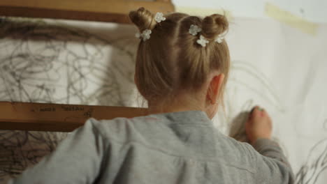 little painter drawing on white wall. talented girl creating artwork indoors.